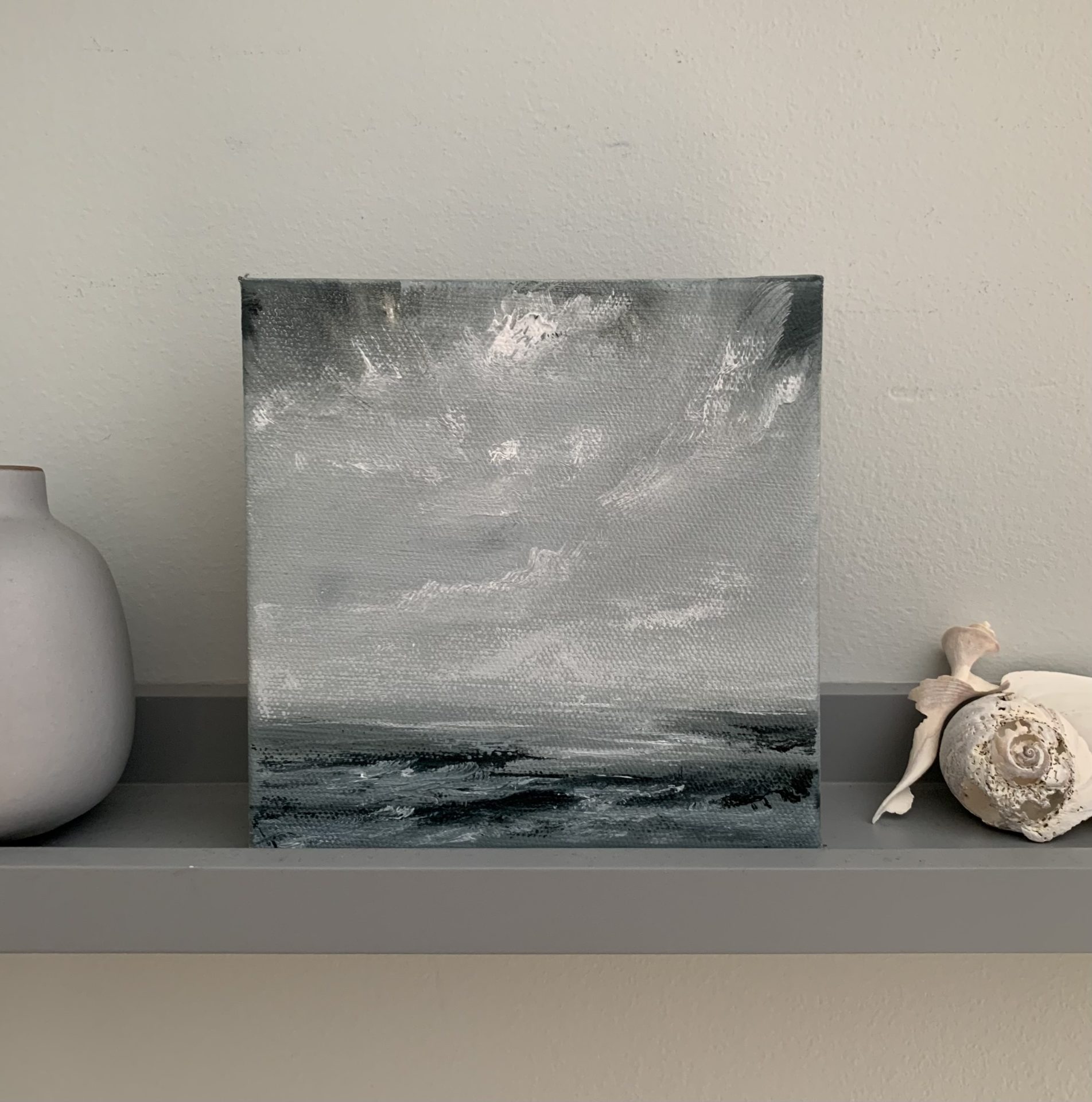 Original seascape oil painting by Tisha Mark, "Wintry Seas No. 5" 6"x6" oil on canvas (2024), shown on a shelf with a small vase and seashells.