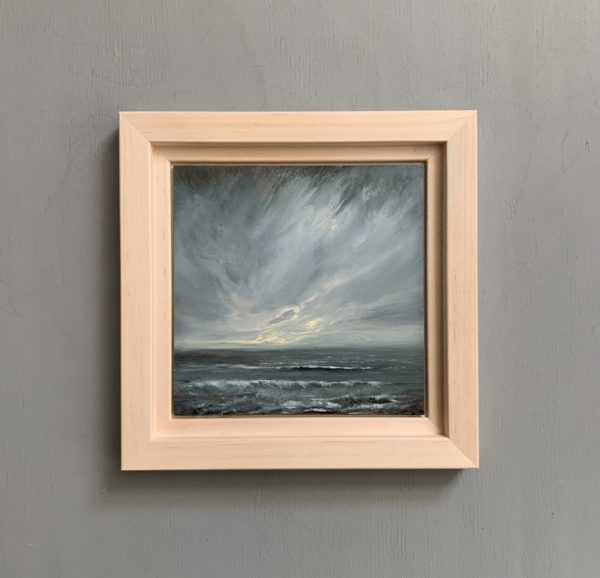 Original seascape oil painting by Tisha Mark, "The Watching" 6"x6" oil on gessobord (2024). Light emerges in a stormy sky over a stormy sea. Shown here in an unfinished maple frame.
